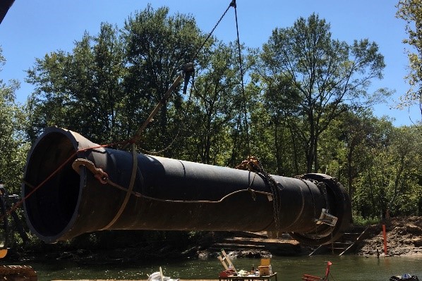 Ductile iron pipe is hoisted into position with chains.